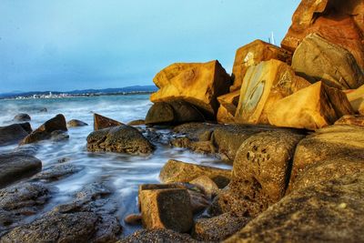 Rocks on beach against clear sky