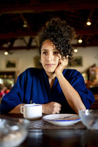 Portrait of young woman using mobile phone while sitting at restaurant