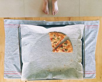 Low section of person standing by pizza on table