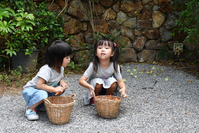 Full length of mother and daughter sitting on wicker basket
