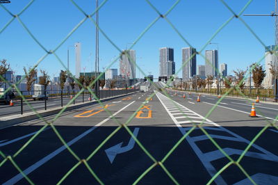 Road by buildings against clear sky