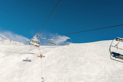 Overhead cable car in snow covered mountains against sky