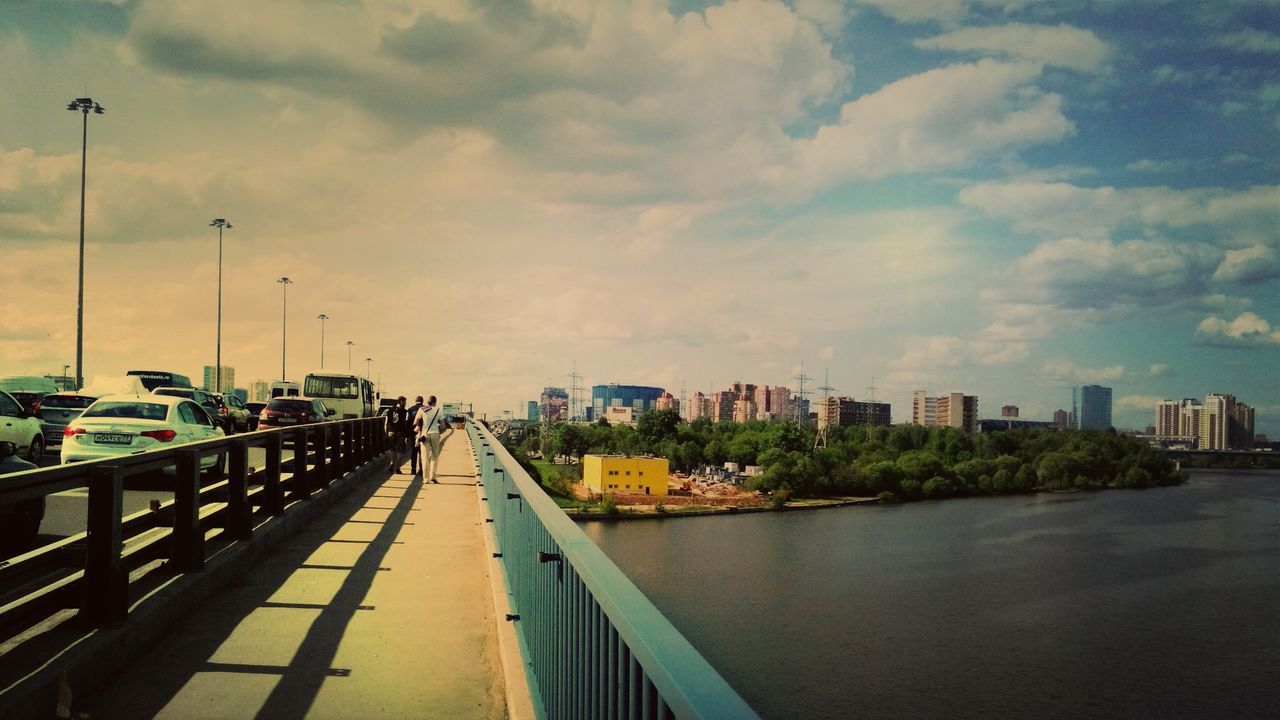 transportation, sky, cloud - sky, the way forward, built structure, city, architecture, water, diminishing perspective, building exterior, cloudy, mode of transport, cloud, vanishing point, railing, car, street light, road, outdoors, weather