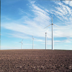 Windmills on field against sky