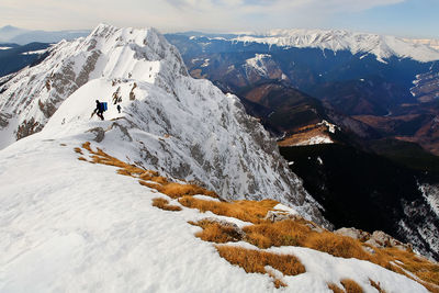 Low angle view of mountaineers climbing snowcapped mountain against sky