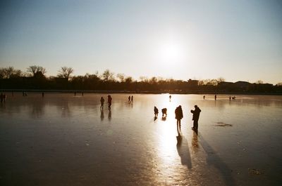 Silhouette people playing on beach against sky