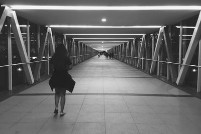 Rear view of woman walking on illuminated elevated walkway