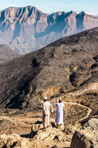 Rear view of people walking on desert against mountains