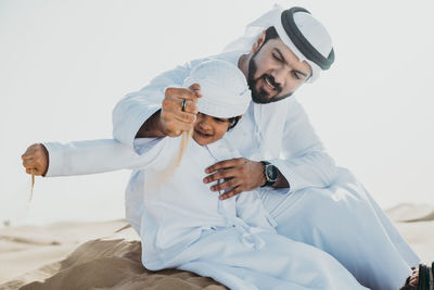 Father and son enjoying while sitting in desert