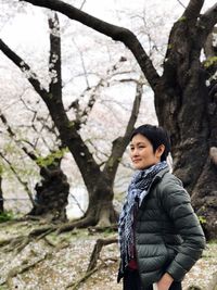 Portrait of woman standing by tree trunk