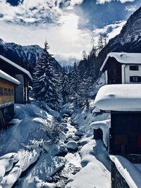 Snow covered houses by buildings against sky