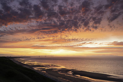 Scenic view of sea against dramatic sky during sunset