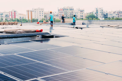 Company of ethnic male workers installing contemporary solar panels in construction site of factory