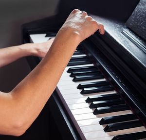 Cropped hand of woman playing piano