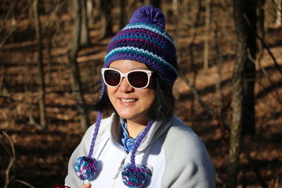 Smiling mature woman wearing knit hat standing in forest