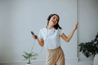 Young girl at home listening to music with headphones and dancing