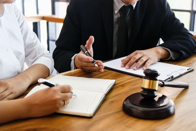 Midsection of man holding paper while sitting on table