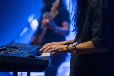 Midsection of male pianist playing piano on stage
