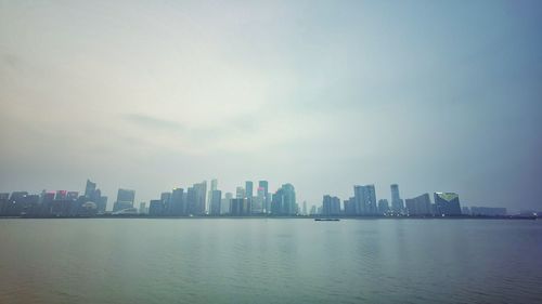 Sea by buildings against sky in city