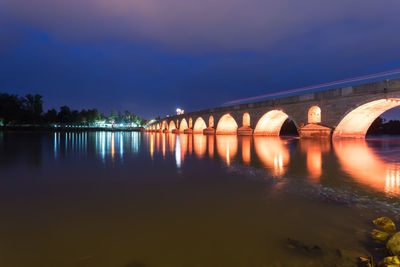 Arch bridge over river against sky at night