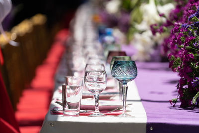 Laid big table with empty dishes near red chairs for holiday on outdoor in sun weather. soft focus.