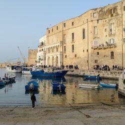 Boats in canal amidst buildings in city against clear sky