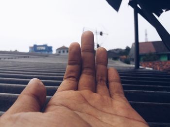 Close-up of man hand against sky