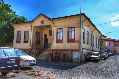 Cars on street by buildings against sky