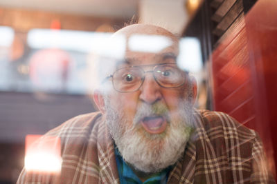 Portrait of shocked senior man seen through glass