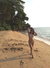 Full length of woman standing on beach against sky