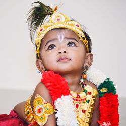 Close-up of cute girl in krishna costume looking up at home