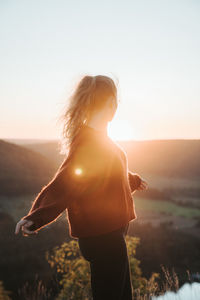 Woman standing against sky during sunset