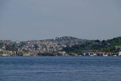 Scenic view of sea by buildings in town against clear sky