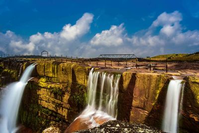 Scenic view of waterfall against sky