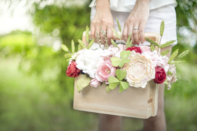 Midsection of woman holding bouquets in bag