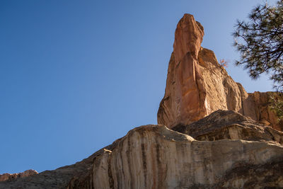 Low angle view of rock formation against clear blue sky