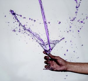 Close-up of hand splashing water against white background