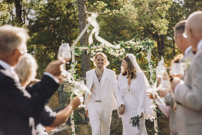 Newlywed mid adult couple holding hands walking amidst guests in wedding ceremony