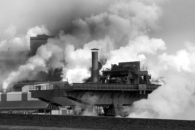 Smoke emitting from factory against sky