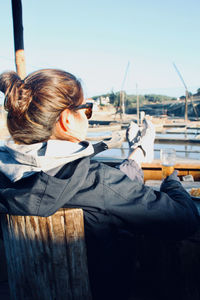 Rear view of woman sitting on boat against sky