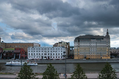 Buildings by river against sky in city