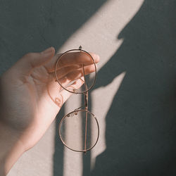 Close-up of hand holding eyeglasses against wall