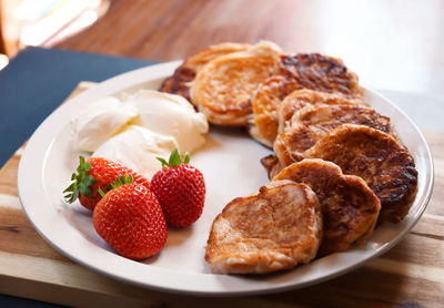 Strawberry fritters with sour cream on a white plate and a board for breakfast,