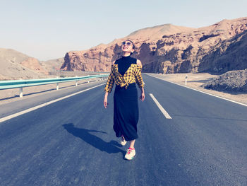 Rear view of man standing on road against mountain range