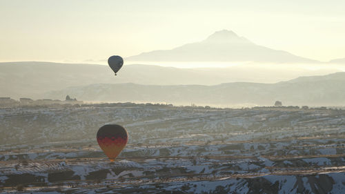 Hot air balloon flying over mountains against sky