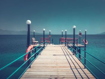 Pier over sea against clear blue sky