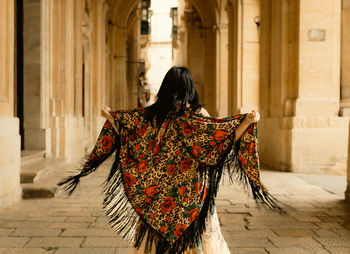 Rear view of woman dancing against historic building