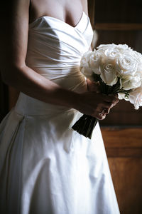 Midsection of bride holding bouquet