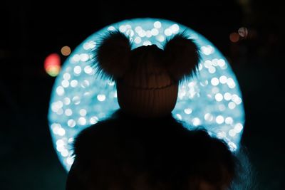 Close-up portrait of silhouette woman standing against illuminated lights