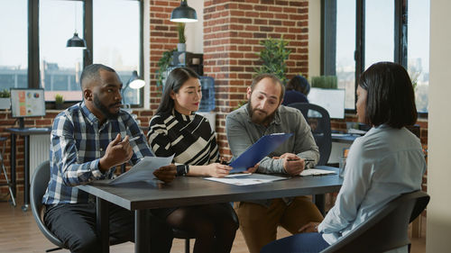 Friends using laptop while sitting on table